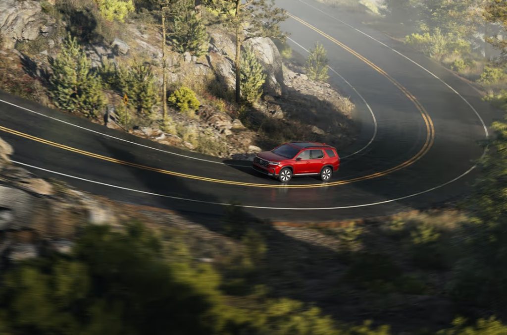 The new 2025 Honda Pilot is seen driving up around curved, mountainous roads. Shop for your new Pilot at Stonecrest Honda.