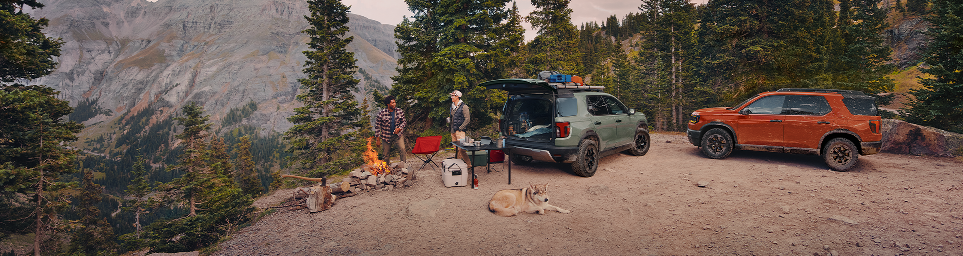 Two Honda Passport vehicles parked by a camping site in the woods.
