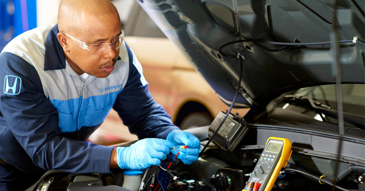 A Honda Service Technician performing a diagnosis on a vehicle's engine in the service center