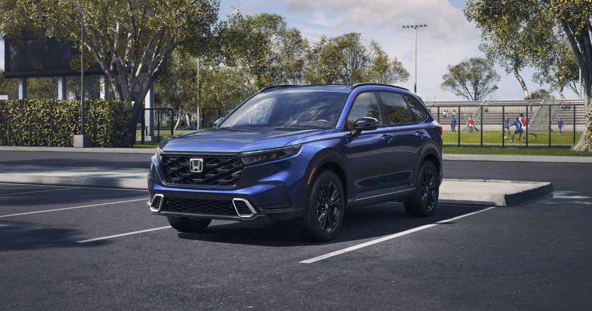 A blue Honda CR-V in a parking lot by a soccer field.