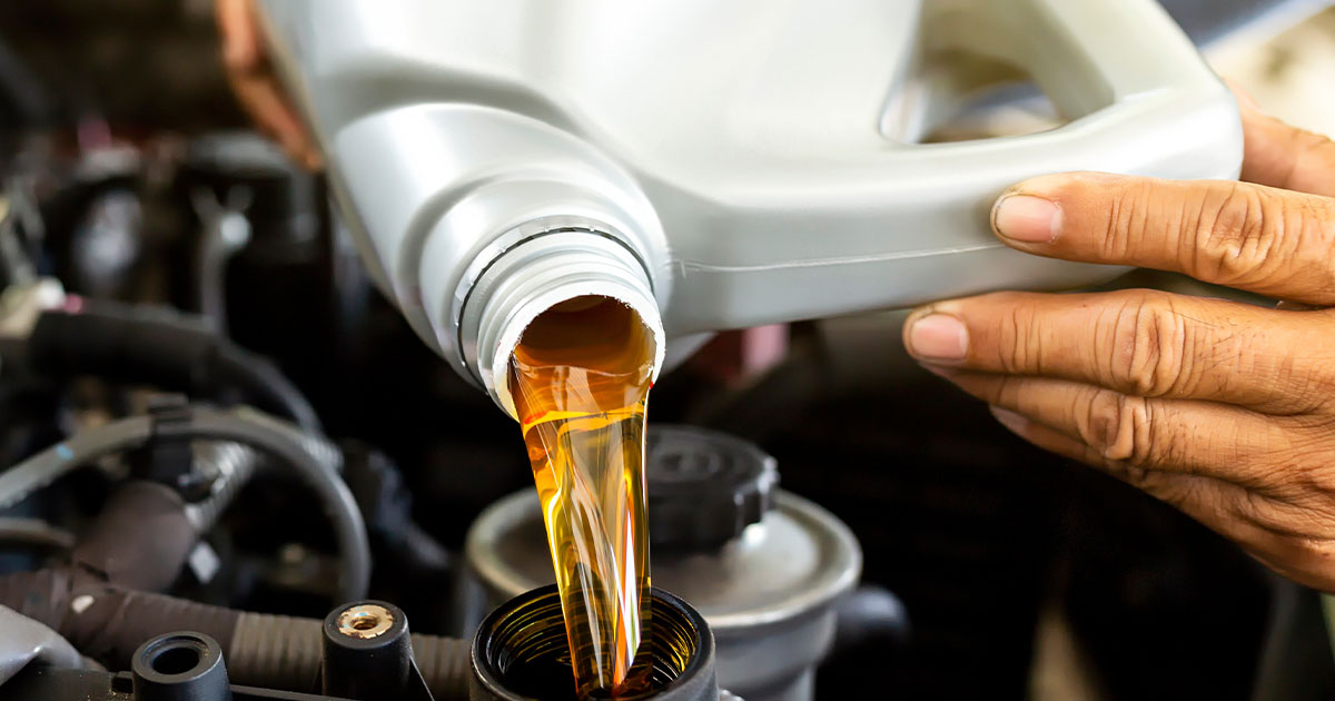 Close-up of a service technician refilling a vehicle's engine oil.