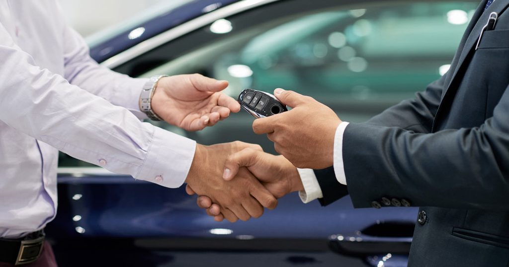 A man is being handed a pair of car keys in a dealership
